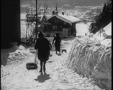 A Group of Female Civilians Skiing down a Snowy Hill with a Picturesque Alpine Village..., 1920. Creator: British Pathe Ltd