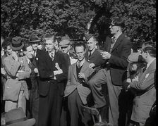 A Group of Male Civilians and One Soldier Listen to a Man With a Cigarette Standing on a..., 1938. Creator: British Pathe Ltd