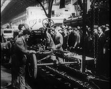 A Group of Male Civilians Building a Car As a Crowd of People Watch. Behind the Crowd..., 1924. Creator: British Pathe Ltd