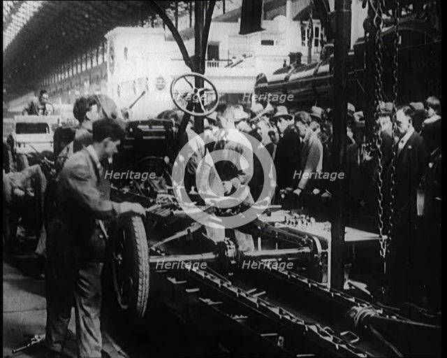 A Group of Male Civilians Building a Car As a Crowd of People Watch. Behind the Crowd..., 1924. Creator: British Pathe Ltd.