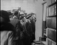 A Group of Male Civilians Looking at a Poster Attached to a Gate, 1926. Creator: British Pathe Ltd