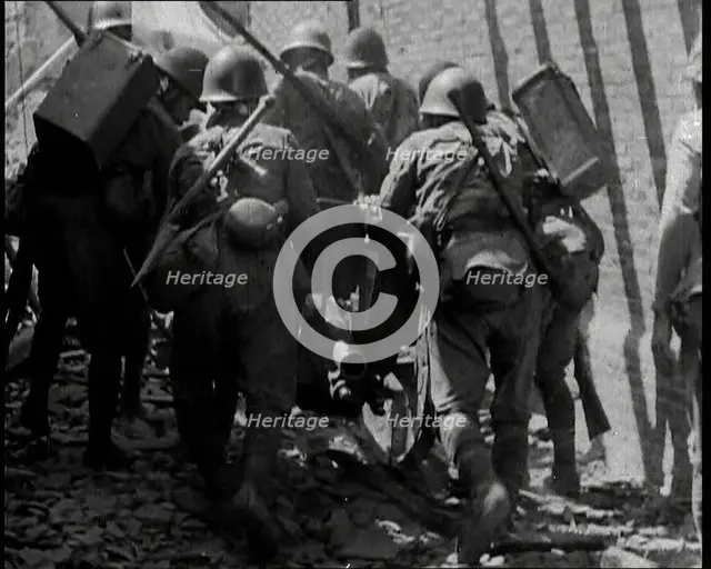 A Group of Male Japanese Soldiers Pushing a Gun Over Rubble in a Street in Shanghai, 1937. Creator: British Pathe Ltd.