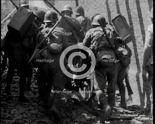 A Group of Male Japanese Soldiers Pushing a Gun Over Rubble in a Street in Shanghai, 1937. Creator: British Pathe Ltd.
