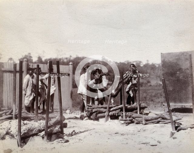 A group of men lower the body of a dead man on to a pyre of logs prior to a Hindu...,  1896/1897. Creator: Unknown.