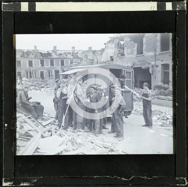 A group of men, possibly rescue workers, outside a tea van on a bomb damaged street, England, 1940-5 Creator: Norman Kingsley Harrison.
