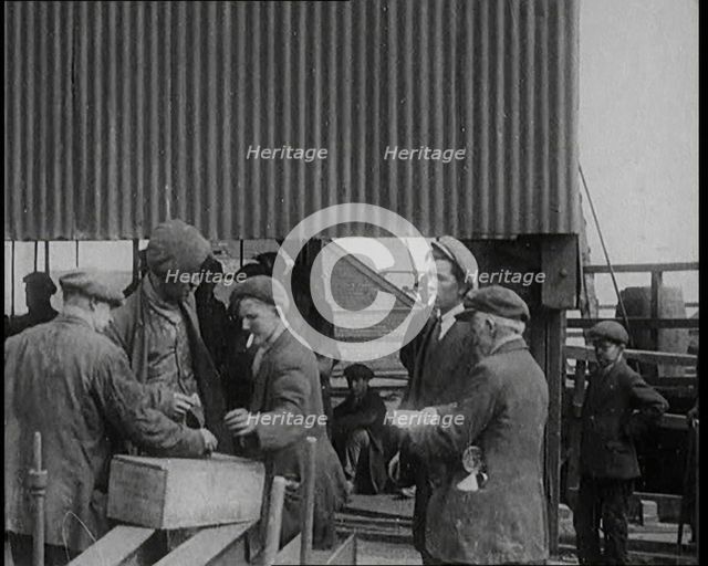 A Group of Miners Gathering and Smoking at a Pit Head, 1920. Creator: British Pathe Ltd.