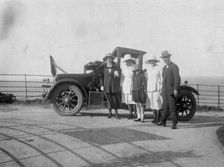 A group of people in front of their car at the seaside, c1920s(?)