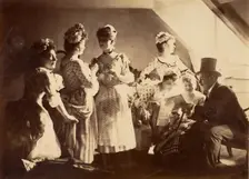 A Group of Six Costumed Women Posed in Interior with Top Hatted Gentlemen, c1885. Creator: Unknown