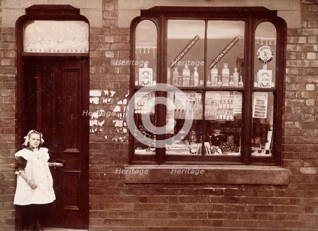 A grocer's shop in England: doorway and shop window, (1900?). Creator: Unknown.