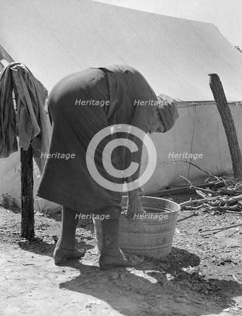 A grandmother washing clothes in a migrant camp, Stanislaus County, California, 1939. Creator: Dorothea Lange.