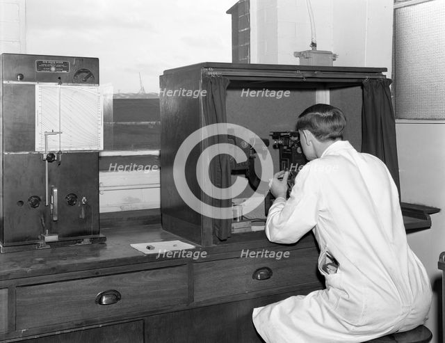 A lab tachnician with a Reichter Microscope at a steelworks, Sheffield, South Yorkshire, 1962. Creator: Michael Walters.
