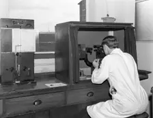A lab tachnician with a Reichter Microscope at a steelworks, Sheffield, South Yorkshire, 1962. Creator: Michael Walters