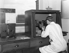 A lab tachnician with a Reichter Microscope at a steelworks, Sheffield, South Yorkshire, 1962. Creator: Michael Walters