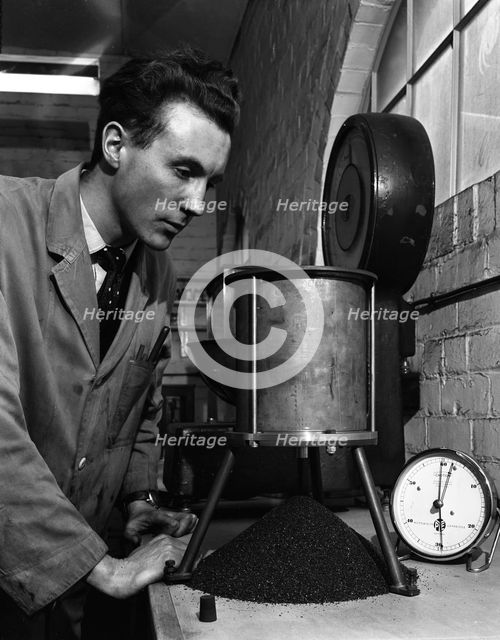 A lab technician undertaking a coal flow test, Mapperley Colliery, Derbyshire, 1962.  Creator: Michael Walters.