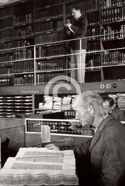 A labourer reads a book in a library, Germany, 1936. Creator: Unknown.