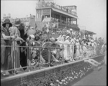 A Large Crowd of Civilians Wearing Smart Outfits and Hats Watching a Horse Race, 1920. Creator: British Pathe Ltd