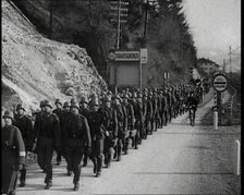 A Line of Male German Soldiers Marching Through a Customs Point Alongside a High Bank..., 1938. Creator: British Pathe Ltd