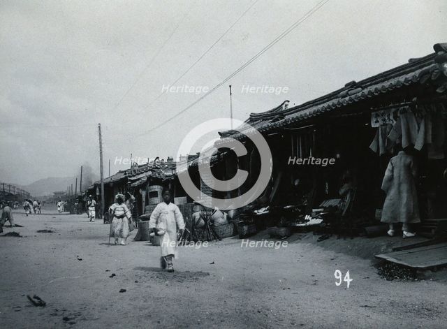 A line of shops beside a dusty street, with telegraph poles overhead, in Korea, c1900. Creator: Unknown.
