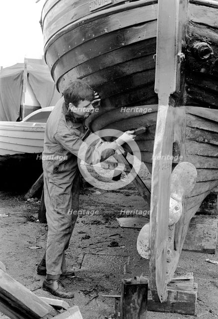 A man cleaning the keel of his sailing boat, Sweden, 1966. Creator: Unknown.