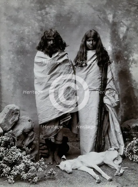 A man and woman of the Toda tribe standing in a photographic studio, with a dog lying..., c1900. Creator: Unknown.