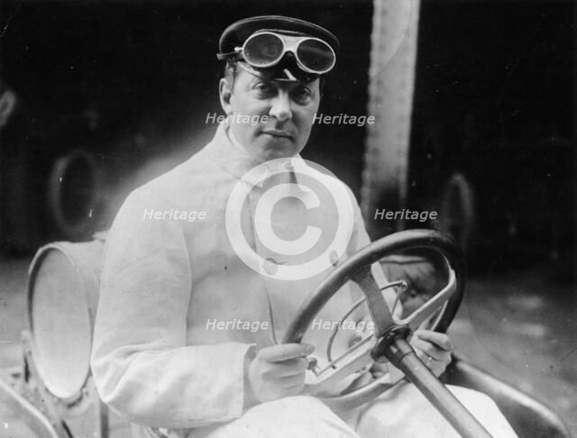 A man at the wheel of his car dressed in a driving coat and goggles. Artist: Unknown