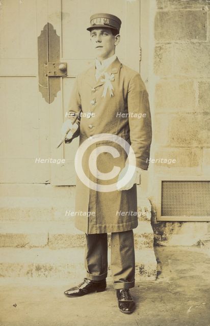 A man dressed wearing a long coat and a hat bearing the word "Cook"...(1910-1919?). Creator: Unknown.