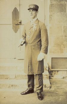 A man dressed wearing a long coat and a hat bearing the word "Cook"...(1910-1919?). Creator: Unknown