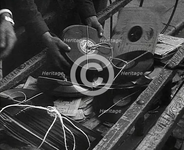 A Man Dumping Old gramophone records to Use for War Materials, 1942. Creator: British Pathe Ltd.