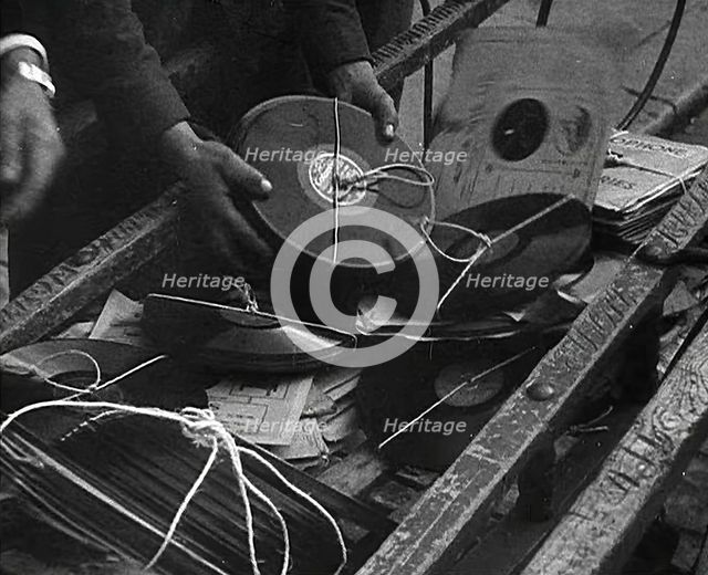 A Man Dumping Old gramophone records to Use for War Materials, 1942. Creator: British Pathe Ltd.