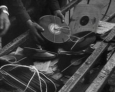 A Man Dumping Old gramophone records to Use for War Materials, 1942. Creator: British Pathe Ltd