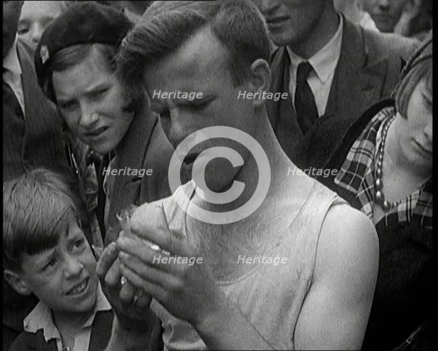 A Man Eating a Glass as the Crowd Behind Him Winces, 1921. Creator: British Pathe Ltd.