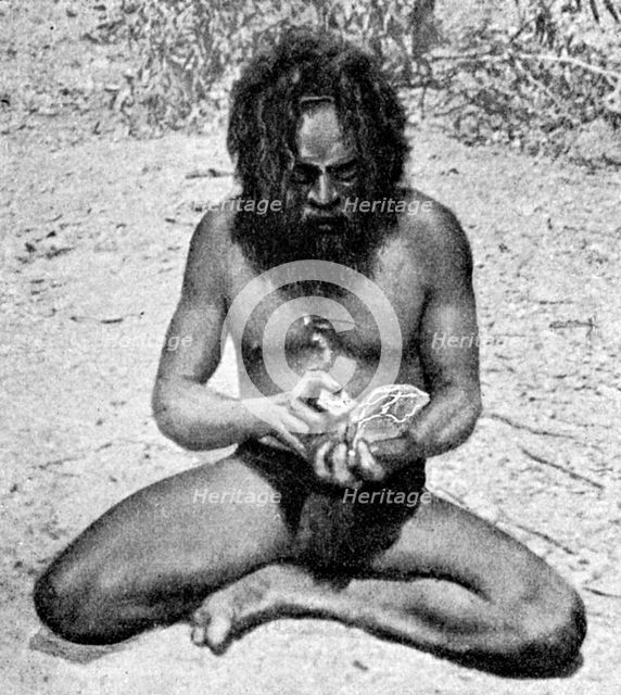 A man from the Warramunga tribe making a stone axe head, Australia, 1922.Artist: Spencer and Gillen