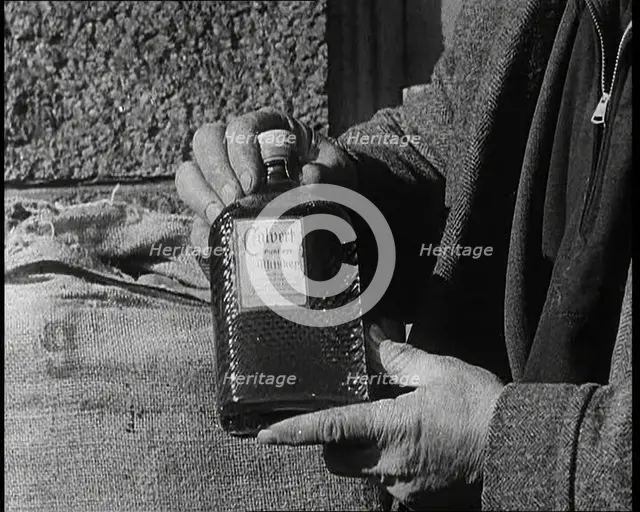 A Man Holding a Bottle of Liquor, 1932. Creator: British Pathe Ltd.