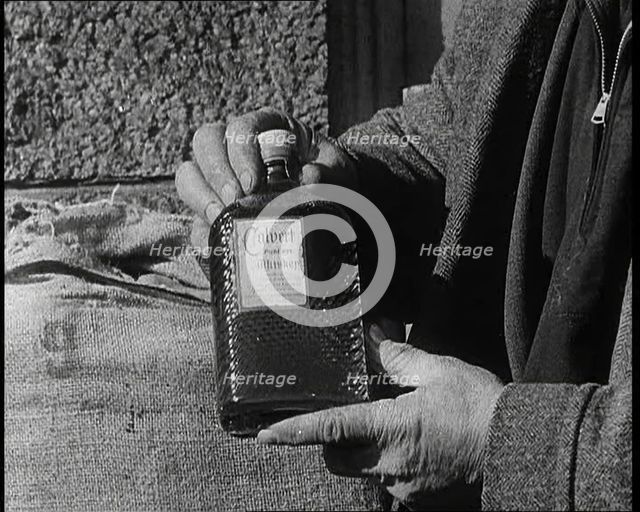 A Man Holding a Bottle of Liquor, 1932. Creator: British Pathe Ltd.