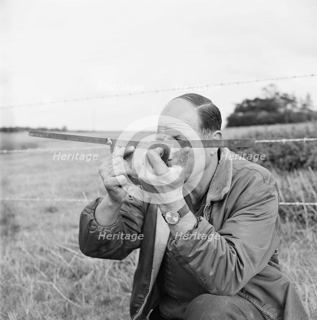 A man holding a surveyor's protractor working on the route of the Mersey oil pipeline, 24/09/1967. Creator: John Laing plc.