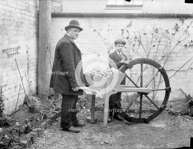 A man holding his potato planting invention, an adapted cartwheel with pockets..., England, 1900. Creator: Henry Taunt.