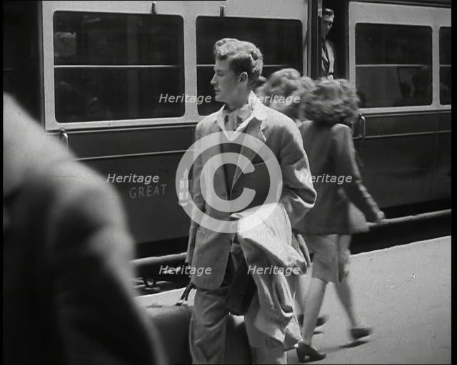 A Man in a Casual Suit and Carrying a Coat and Suitcase Walking Along a Platform Having..., 1938. Creator: British Pathe Ltd.