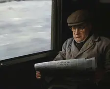 A Man in a Flat Cap and Spectacles Reading a Folded Newspaper in the Window Seat of a Train..., 1938 Creator: British Pathe Ltd