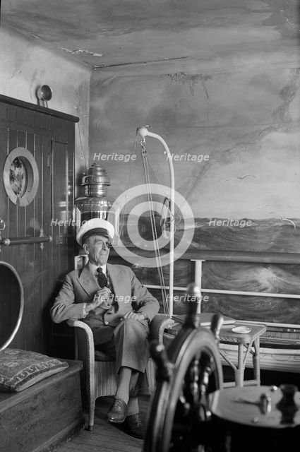 A man in a sailor's cap and eyepatch sits in a reconstructed ship's cabin, c1945-c1965. Artist: SW Rawlings