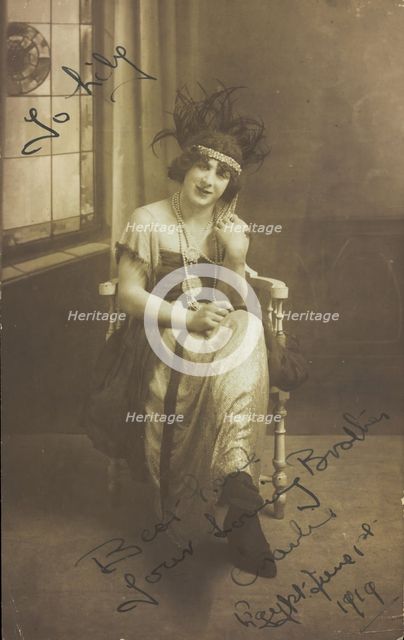 A man in drag (Charlie) sits face-on, wearing detailed costume, with a window painted..., 1919. Creator: Unknown.