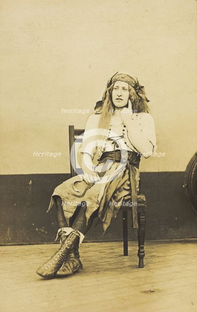 A man in drag sits pensively on a chair, on the deck of a ship, (between 1910 and 1919?). Creator: Unknown.