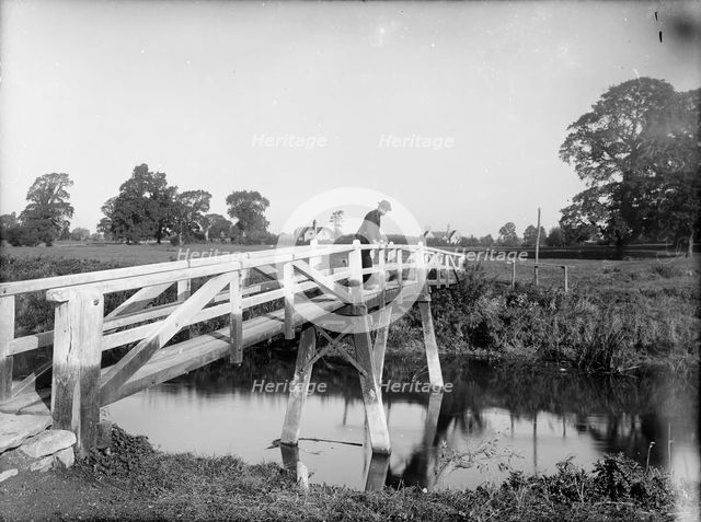 A man looking over the Eisey Footbridge into the River Thames, Cricklade, Wiltshire, c1860-c1922. Artist: Henry Taunt