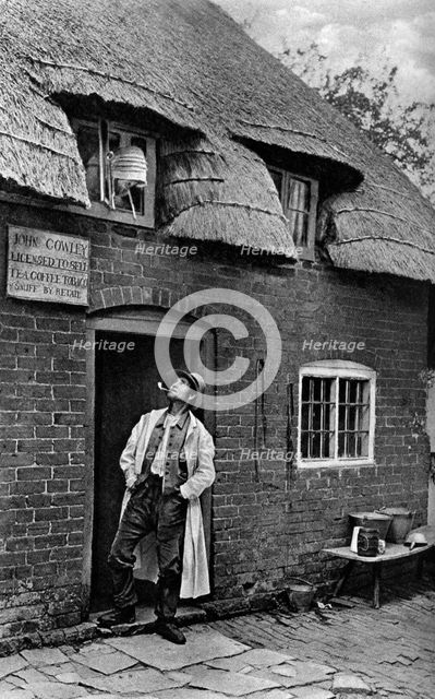A man smoking a pipe outside a shop, Worcestershire, c1922.Artist: AW Cutler