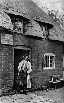 A man smoking a pipe outside a shop, Worcestershire, c1922.Artist: AW Cutler