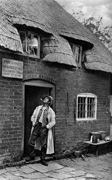 A man smoking a pipe outside a shop, Worcestershire, c1922.Artist: AW Cutler