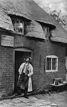 A man smoking a pipe outside a shop, Worcestershire, c1922.Artist: AW Cutler