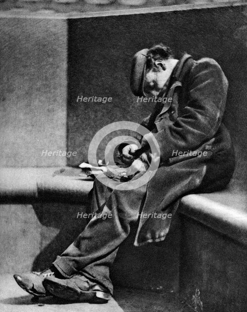 A man sleeping on Blackfriars Bridge, London, 1926-1927.Artist: Walter Benington