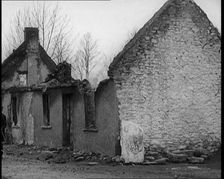 A Man Standing Outside a Burnt Out Cottage in Ireland, Holding a Bicycle, 1921. Creator: British Pathe Ltd