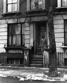 A man standing outside a house in Westbourne Grove, possibly in Kensington, London, 1950s. Creator: Henry Grant