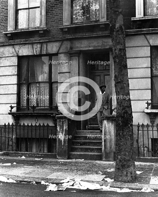 A man standing outside a house in Westbourne Grove, possibly in Kensington, London, 1950s. Creator: Henry Grant.